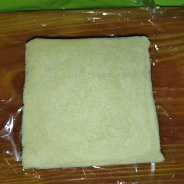 Siapkan plastik wrap paling bawah, lalu taruh 1 lembar roti tawar diatasnya.