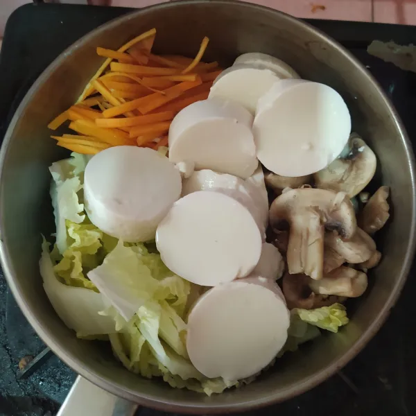 Tata daun sawi putih, wortel, jamur kancing dan tofu di panci kecil.
