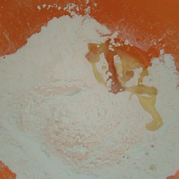 Untuk membuat kue beras (tteok), siapkan wadah dan masukkan tepung beras, tepung tapioka, dan minyak goreng, lalu aduk rata.