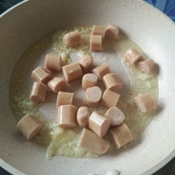 Tumis bawang putih hingga harum lalu masukkan irisan sosis. Aduk rata.