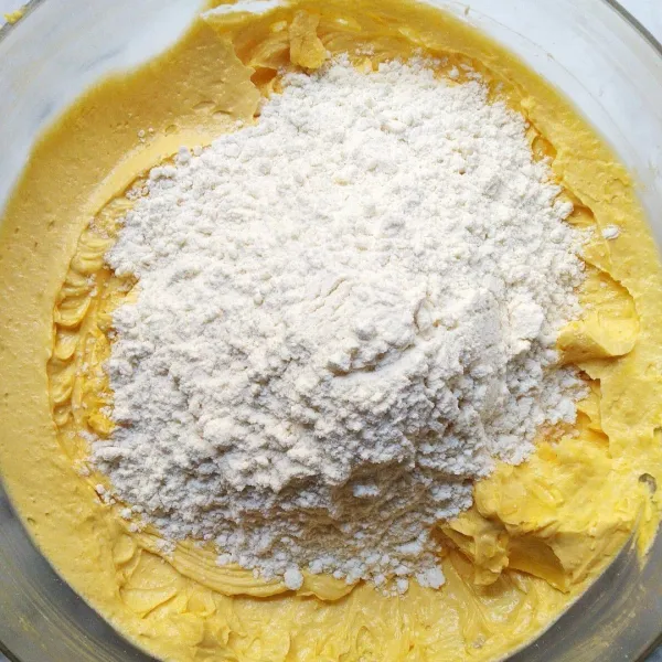 Matikan mixer, lalu masukkan ayakan tepung terigu dan baking powder sedikit demi sedikit ke dalam adonan. Aduk rata.