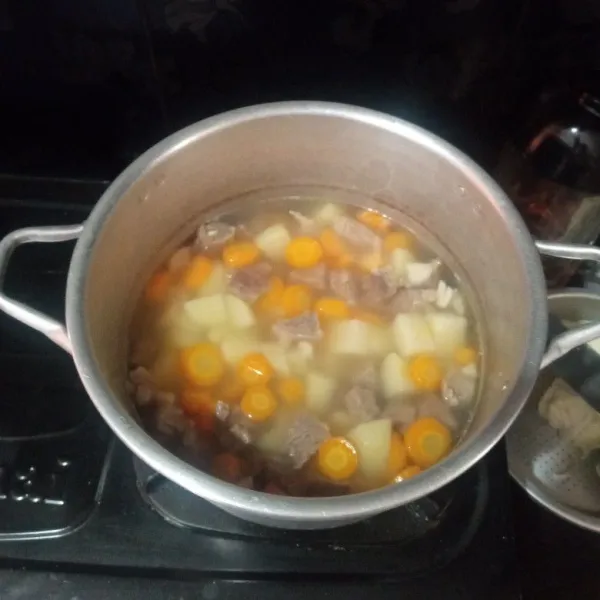 Masukkan bawang putih, wortel dan kentang. Masak hingga layu.