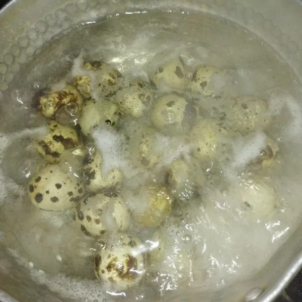 Bilas telur puyuh dengan air lalu rebus dengan air secukupnya. Rebus selama 15 menit hingga telur matang, buang airnya lalu angkat telurnya.
