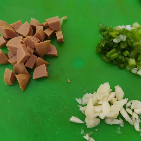 Cincang halus bawang putih, potong kasar daun bawang dan sosis sapi. Sisihkan.