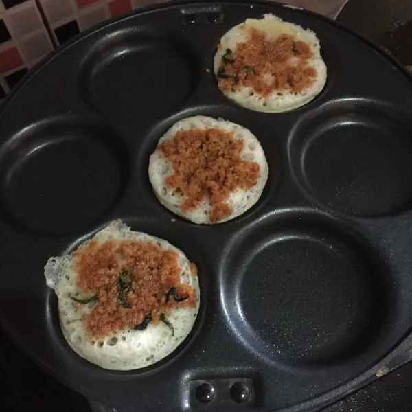 Setelah adonan didiamkan, cetak di atas panggangan anti lengket (cetakan serabi) lalu tambahkan topping oncom di atasnya. Panggang sampai matang. Sajikan.