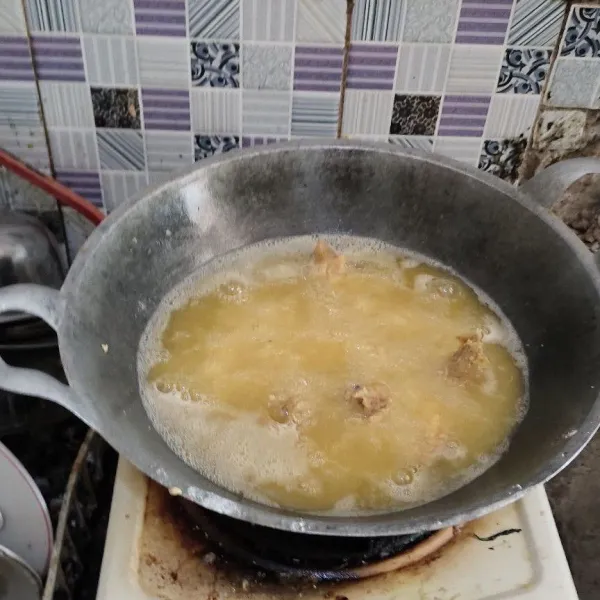 Panaskan minyak menggunakan api kecil, minyaknya harus benar-benar panas kemudian goreng ayam hingga berwarna kuning keemasan.