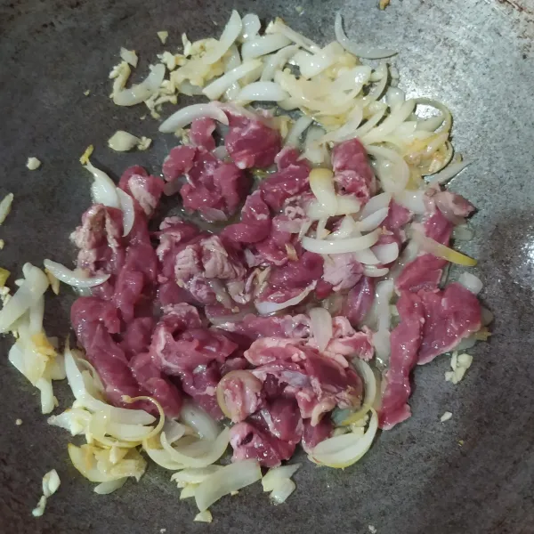 Tumis bawang bombay hingga layu lalu lalu masukkan bawang putih cincang dan masak sampai harum. Setelah harum masukkan irisan daging. Masak sampai berubah warna.