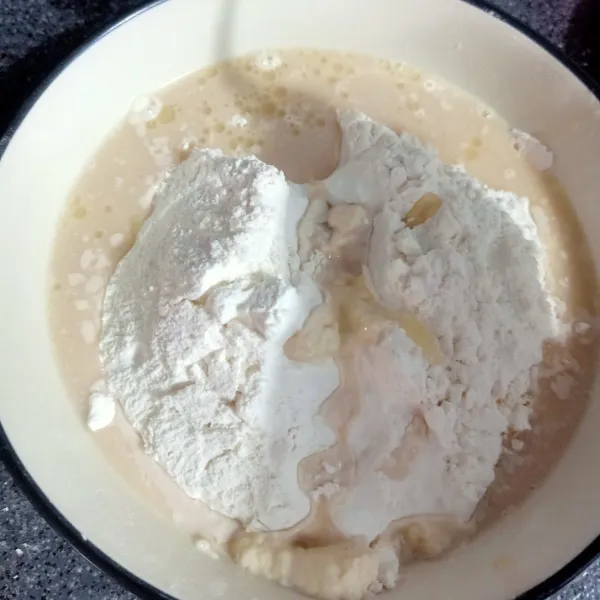 Setelah 10 menit, tuang air ragi. Lalu masukan sisa air adun rata.