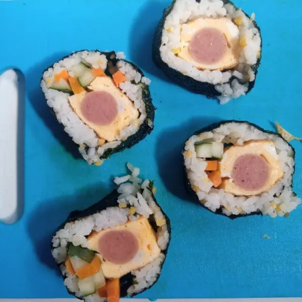 Potong-potong kimbab. Menggunakan pisau yang tajam. Kemudian sajikan bersama saosnya.