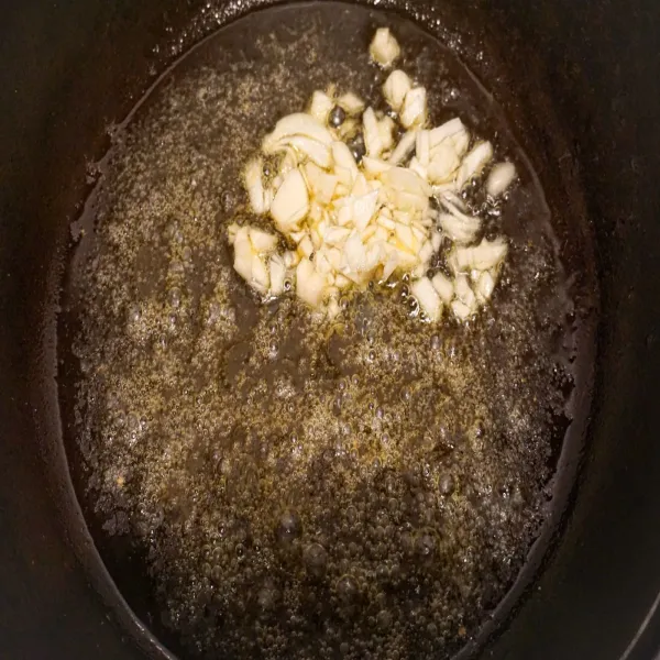 Tumis bawang putih ke dalam minyak yang telah panas.