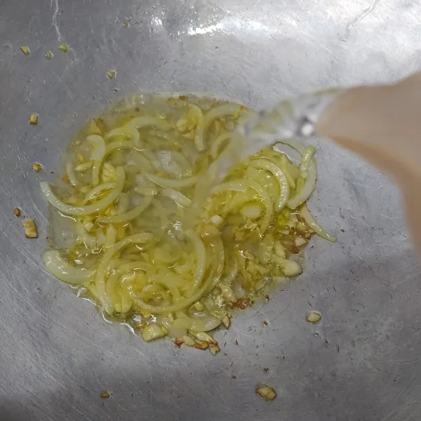 Tumis bawang putih dan bawang bombay dengan sedikit minyak sampai layu dan harum. Masukkan air lalu aduk rata.
