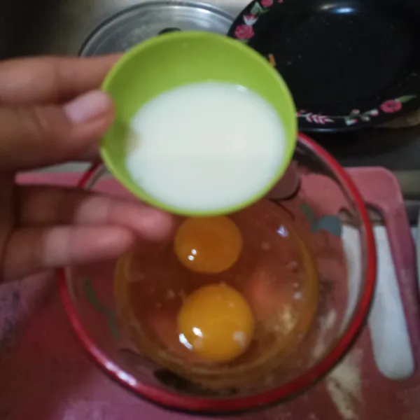 Kocok telur dengan susu cair.