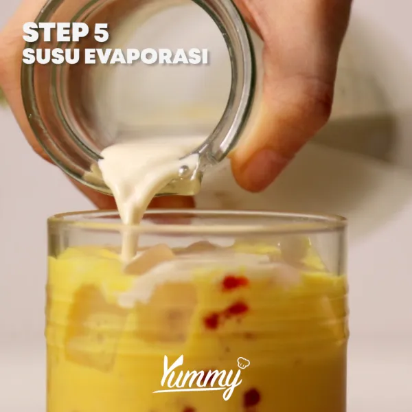 Tuangkan susu evaporasi hingga penuh dan hiasi dengan potongan buah nanas.
