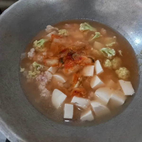 Selanjutnya, masukkan kembang kol, dan kimchi, masak sebentar lalu tambahkan air dan masukkan tahu.