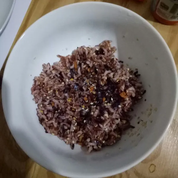 Tambahkan minyak wijen dan nori bubuk serta garam ke dalam nasi