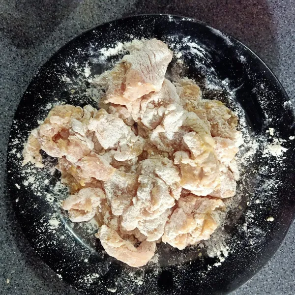 Setelah 15 menit, masukan tepung. Aduk hingga rata, pastikan ayam terbalur sempurna oleh tepung di seluruh sisinya. Setelah itu masukkan putih telur, aduk hingga rata.