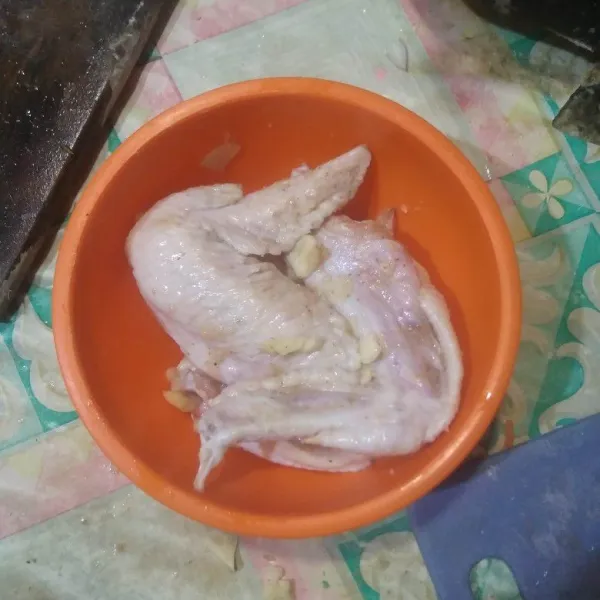 Bersihkan sayap ayam lalu marinasi dengan bawang putih cincang, garam, dan lada bubuk. Aduk rata.