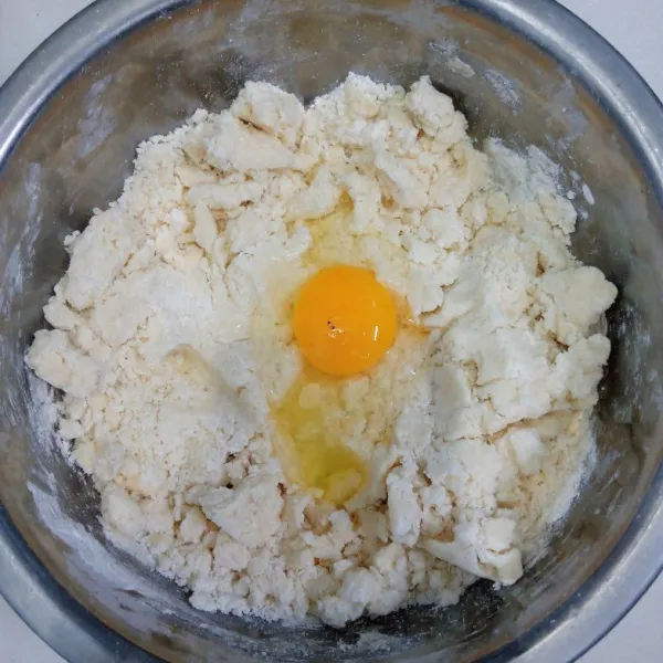 Kemudian tuang ke dalam campuran tepung. Uleni sampai tercampur rata. Masukkan telur dan susu kental manis. Uleni kembali sampai tercampur rata.