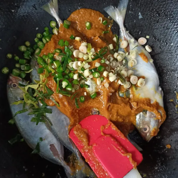 Tuang bumbu halus, daun jeruk, serai dan cabe hijau ke dalam ikan.