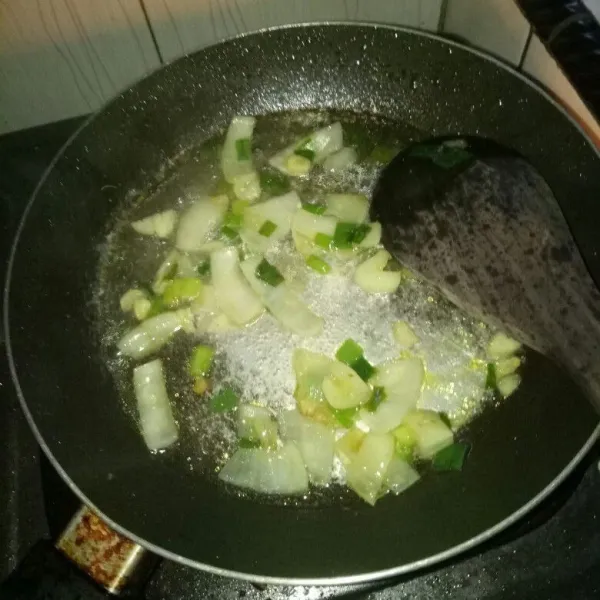 Siapkan pan dan panaskan minyak. Tumis bawang putih dan bawang bombay sampai harum, lalu masukan daun bawang. Aduk rata, tuang air, dan masak sampai mendidih.