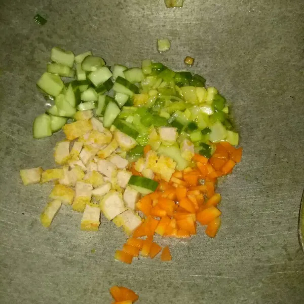 Masih di pan yang sama, tumis bawang putih dan bombay sampai harum. Masukkan wortel, timun, dan nugget. Aduk rata.