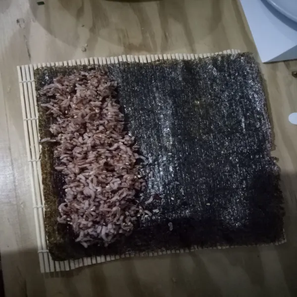 Ratakan nasi lalu tambahkan isian ke atas nasi dan gulung. Oleskan nori dengan sedikit minyak wijen agar tidak lepas. Potong dan sajikan.