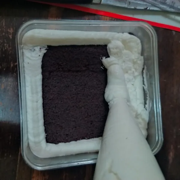Beri whipped cream secukupnya di dasar box (boleh diskip dan langsung potongan cake). Letakkan 1 potong cake, siram dengan cairan milkbath secukupnya. Beri whipped cream lalu ratakan.