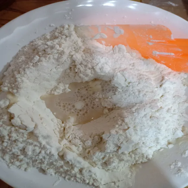 Jika ragi sudah bisa digunakan, campur ragi sedikit-sedikit sambil aduk tepung.