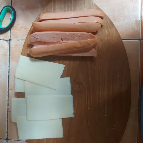 Belah sosis menjadi 4 bagian, kemudian belah keju lembaran (slice) menjadi 2 bagian.