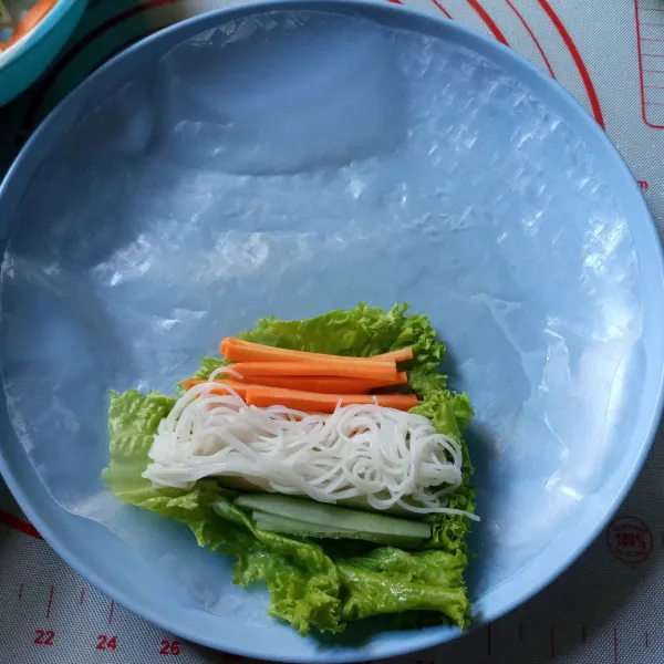 Letakkan selembar daun selada sebagai alas kemudian timpa dengan wortel, timun dan bihun.