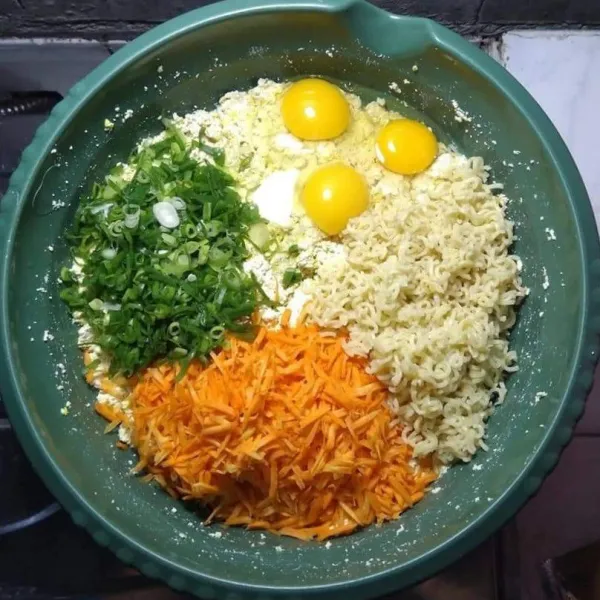 Siapkan wadah, haluskan tahu. Masukkan telur, mie, wortel, daun bawang, bawang merah, bawang putih, kaldu bubuk, merica bubuk, bumbu mie instan, dan garam.