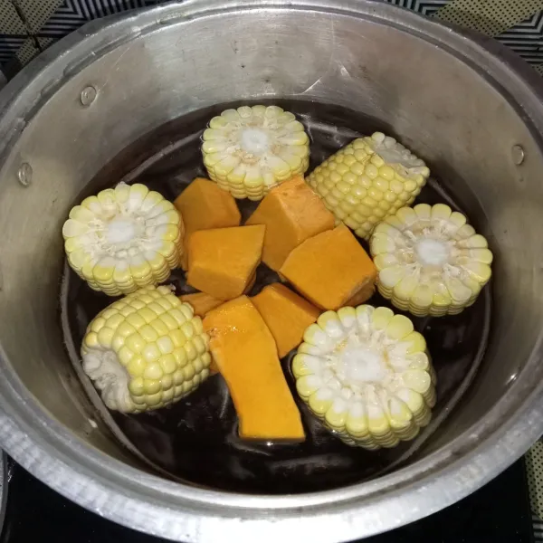 Masukkan labu kuning, jagung dan air ke dalam panci.