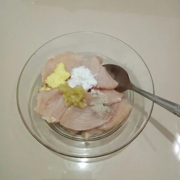 Potong dada ayam tipis melebar, lalu masukkan ke dalam mangkok. Tambahkan bawang putih, merica bubuk, kaldu bubuk, dan garam. Aduk rata.