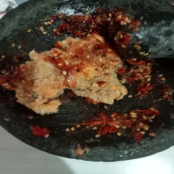 Geprek ayam di atas sambal, lalu hidangkan bersama nasi, potongan mentimun dan tomat.
