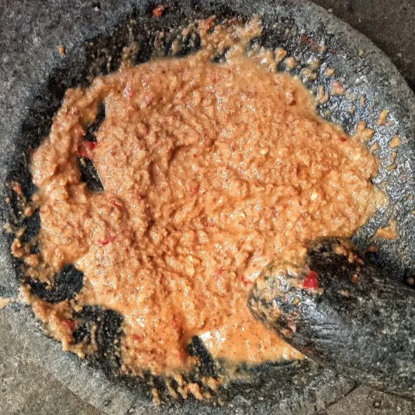 Masukkan air asam jawa sedikit demi sedikit sambil terus diuleg hingga tercampur rata. Tes rasa.