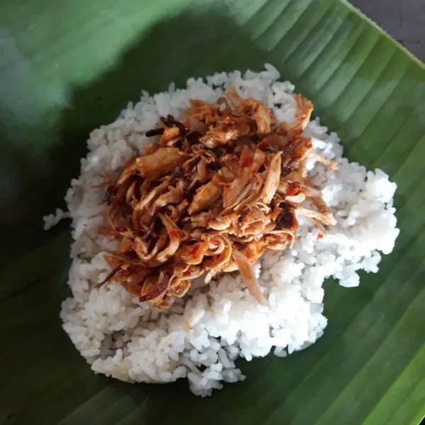 Siapkan daun pisang lalu ambil secukupnya nasi gurih, lalu tambahkan ayam suwir diatasnya, gulung dan semat kedua ujungnya dengan lidi.