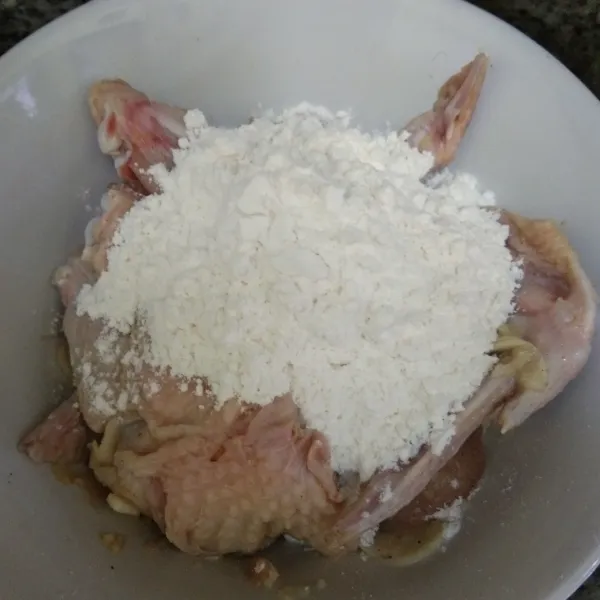 Tambahkan tepung terigu pada ayam, aduk rata.