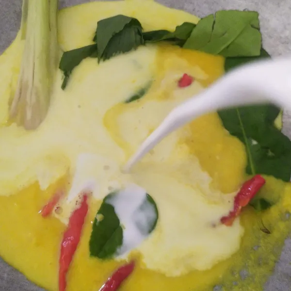 Campur bumbu halus, serai, daun-daun, dan cabe bersama santan, aduk.