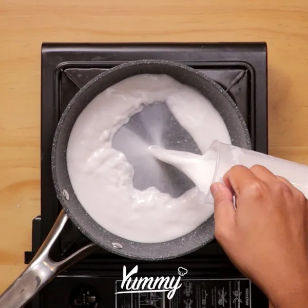 Siapkan panci lalu tuangkan santan dan daun pandan masak dan aduk hingga mendidih. Kemudian sisihkan.