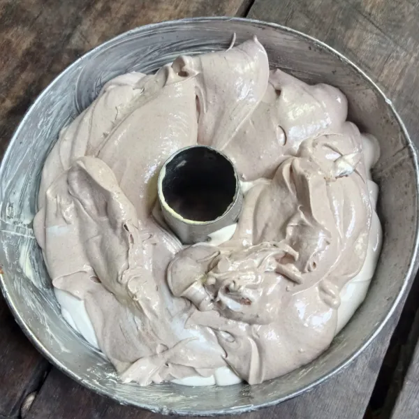 Masukkan pasta cokelat kedalam sisa adonan dan aduk hingga tercampur rata. Lalu tuang di atas adonan putih, gunakan sumpit untuk membuat motif marble pada adonan.