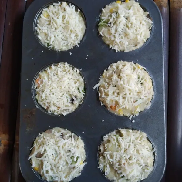 Siapkan cetakan muffin, olesi dengan margarin lalu masukkan adonan kentang. Beri taburan keju.