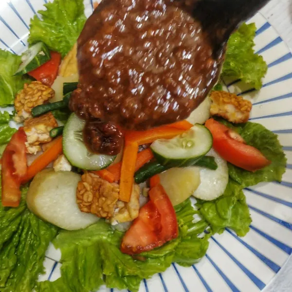 Lalu siram dengan bumbu kacang, tambahkan kerupuk dan telur rebus diatasnya lalu sajikan.