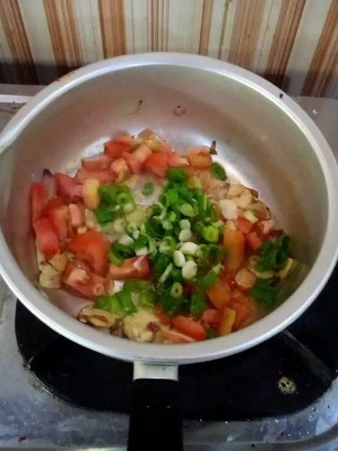 Masukkan tomat dan daun bawang, tumis dan hancurkan tomat