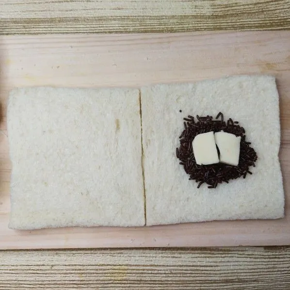 Siapkan 2 lembar roti tawar. Letakkan Meises dan keju di tengahnya. Tutup dengan lembar roti yang lain.