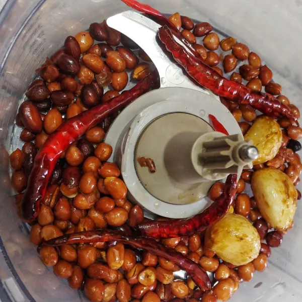 Masukan kacang tanah goreng, cabe merah goreng dan bawang putih goreng ke dalam chopper lalu haluskan.