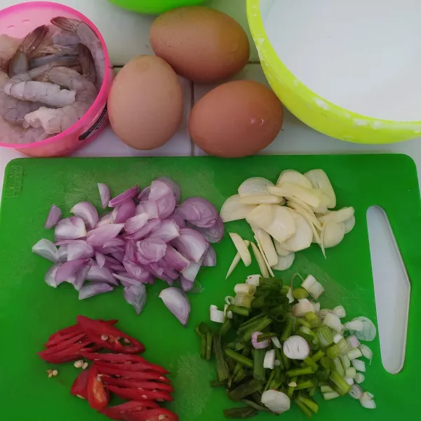Siapkan semua bahan, iris tipis bawang merah dan bawang putih. Potong serong cabe merah besar dan potong kasar daun bawang. Bersihkan udang, buang kepala, kotoran dan kulit.