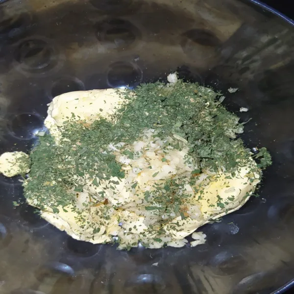 Campur mentega, bawang putih cincang, bawang putih bubuk, dan juga parsley dalam mangkuk.