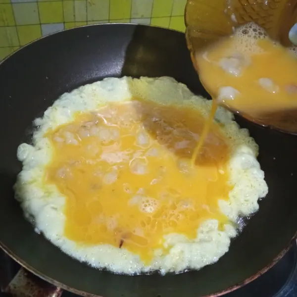 Panaskan minyak, goreng di dalam  frypan. Tuang adonan telur, ratakan telur ke seluruh permukaan wajan. Atur kompor ke api sedang cenderung kecil.