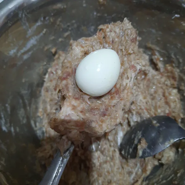 Ambil adonan secukupnya, pipihkan. Beri telur puyuh rebus di atasnya. Tutup telur dengan adonan daging. Bulatkan.