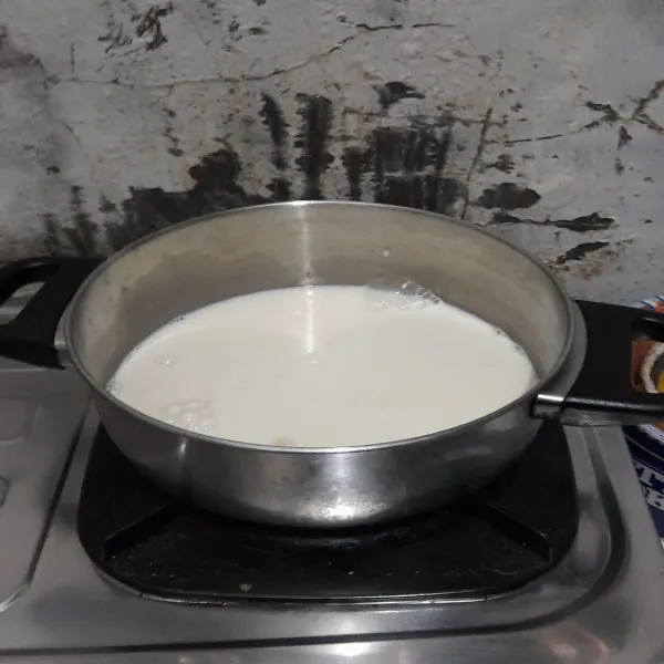 Sambil menunggu puding mangga mengeras, siapkan panci dan campurkan bubuk agar-agar dengan susu dan gula, lalu masak hingga mendidih.